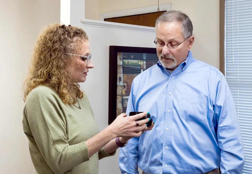 Audiologist showing a hearing aid case to a patient